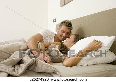 Young attractive couple cuddling in bed View Large Photo Image Stock Image - Young attractive couple cuddling in bed. Fotosearch