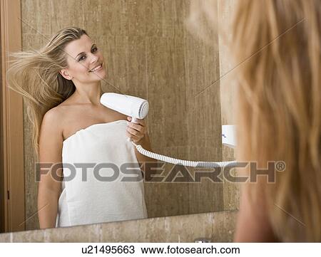 Stock Image - Young beautiful woman using hairdryer. Fotosearch