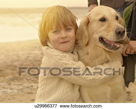 Stock Photo - Young boy embracing dog. Beach. Fotosearch