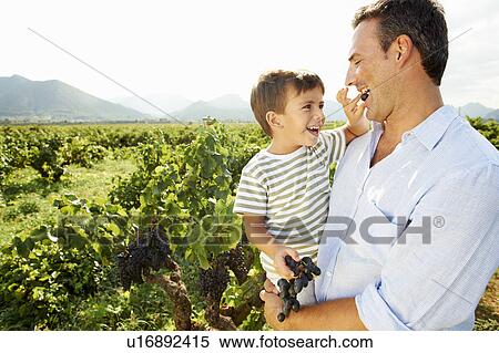 Stock Photography - Young boy feeding father grapes. Fotosearch