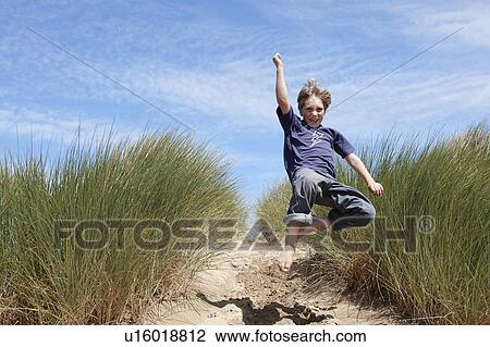 Young boy jumping in sand dunes View Large Photo Image Stock Image - Young boy jumping in sand dunes. Fotosearch