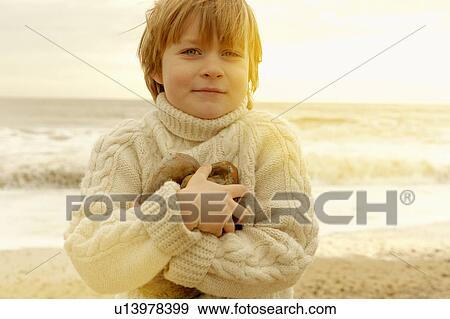 Young boy on a beach holding stones View Large Photo Image Stock Photo - Young boy on a beach holding stones. Fotosearch