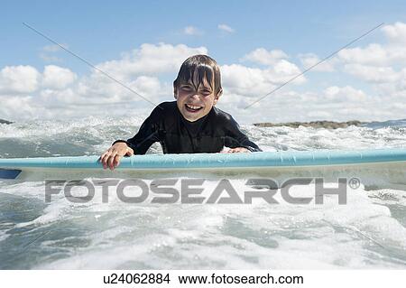 Picture - Young boy on surf board in the sea. Fotosearch