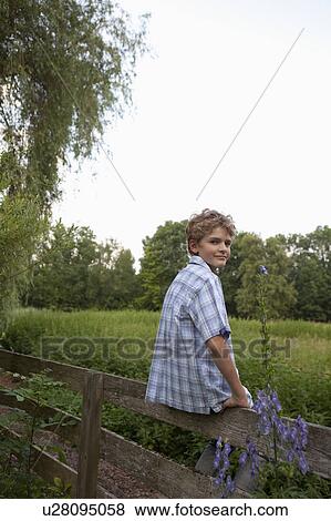 Young boy sitting on fence View Large Photo Image Stock Photo - Young boy sitting on fence. Fotosearch