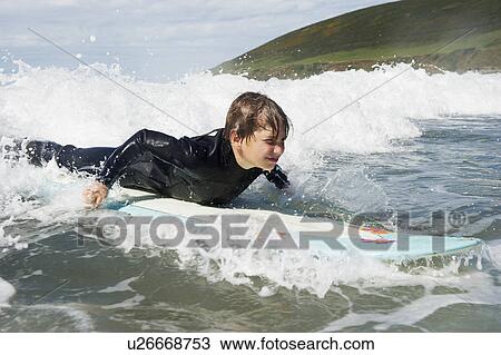 Stock Image - Young boy surfing on a wave. Fotosearch