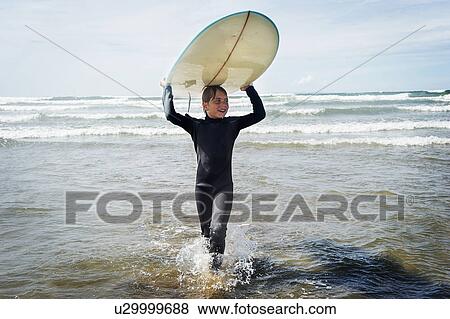 Stock Photo - Young boy with surf board on his head. Fotosearch