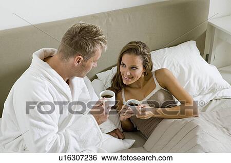 Stock Photograph - Young couple drinking coffee in bed. Fotosearch