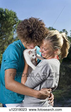 Stock Image - Young couple group hug with kitten. Fotosearch