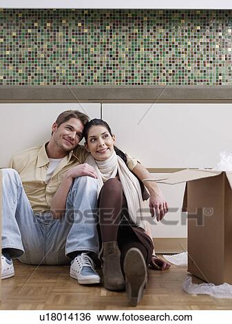 Stock Photograph - Young couple having a break while unpacking. Fotosearch