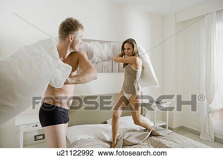 Young couple having pillow fight on bed View Large Photo Image Stock Image - Young couple having pillow fight on bed. Fotosearch