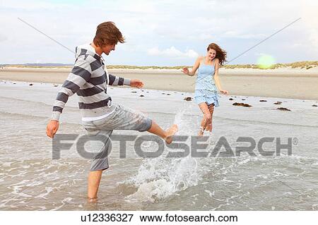 Young couple playing in the surf View Large Photo Image Stock Photo - Young couple playing in the surf. Fotosearch
