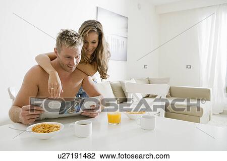 Young couple read paper at breakfast View Large Photo Image Stock Image - Young couple read paper at breakfast. Fotosearch