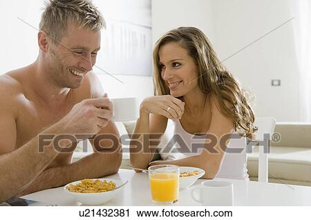 Young couple smiling over breakfast View Large Photo Image Stock Image - Young couple smiling over breakfast. Fotosearch