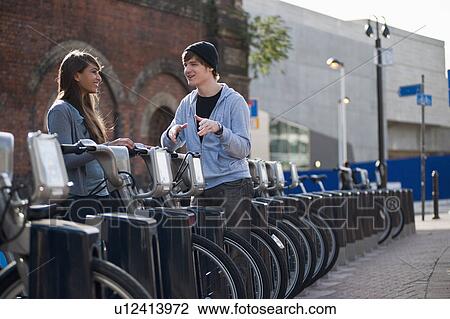 Young couple talking with rented bicycle View Large Photo Image Stock Image - Young couple talking with rented bicycle. Fotosearch