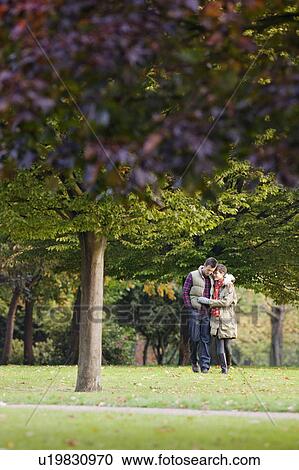 Stock Image - Young couple walking through the park. Fotosearch