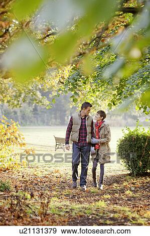 Young couple walking through the park View Large Photo Image Stock Photo - Young couple walking through the park. Fotosearch