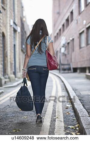 Stock Photo - Young female walking in street with bag. Fotosearch