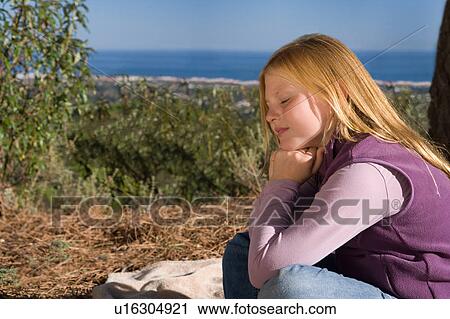 Stock Image - Young girl daydreaming in rural scene. Fotosearch