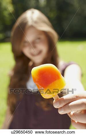 Young girl eating a popsicle in a park View Large Photo Image Stock Image - Young girl eating a popsicle in a park. Fotosearch