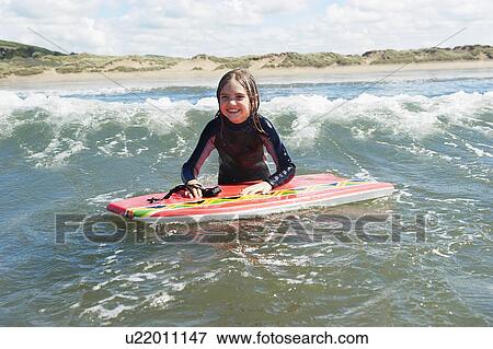 Young Girl in the sea with surf board View Large Photo Image Stock Photo - Young Girl in the sea with surf board. Fotosearch