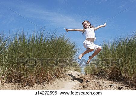 Stock Photography - Young Girl Jumping in Sand dunes. Fotosearch