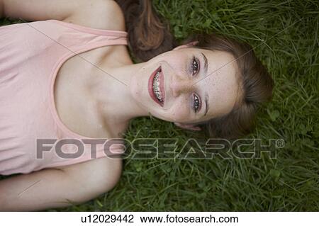 Stock Image - Young girl laying in the grass in a park. Fotosearch