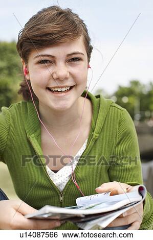 Stock Photograph - Young girl listening to ipod & reading. Fotosearch