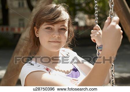 Stock Photograph - Young girl sitting on a swing in a park. Fotosearch