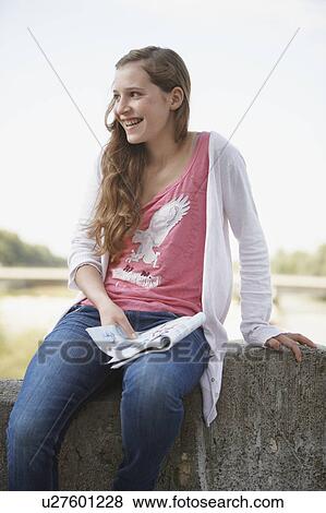 Stock Photo - Young girl sitting on stone wall. Fotosearch