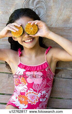 Young girl using half fruits as eyes View Large Photo Image Stock Photo - Young girl using half fruits as eyes. Fotosearch