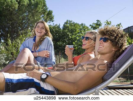 Young group drink, relax, laugh in sun View Large Photo Image Stock Photo - Young group drink, relax, laugh in sun. Fotosearch