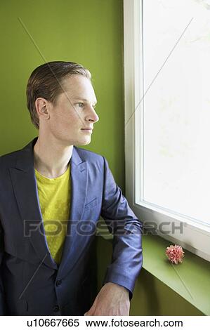 Stock Photography - Young male looking through window. Fotosearch