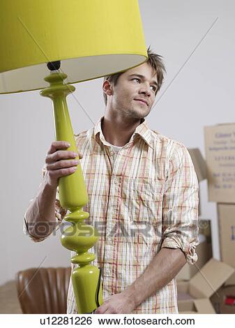 Stock Photograph - Young man carrying lamp. Fotosearch