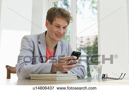 Stock Photo - Young man checking his phone. Fotosearch