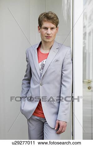 Stock Image - Young man leaning on door. Fotosearch