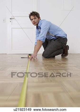 Stock Photo - Young man measuring flat. Fotosearch