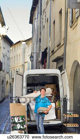 Stock Image - Young man moving in street with rug. Fotosearch