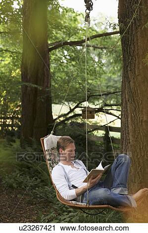 Stock Image - Young man reading in hammock. Fotosearch