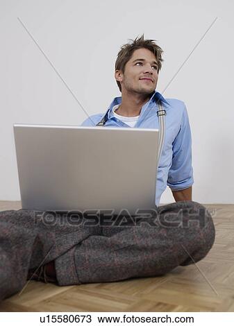 Stock Image - Young man with laptop in empty flat. Fotosearch