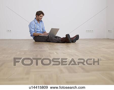 Young man with laptop in empty flat View Large Photo Image Stock Photo - Young man with laptop in empty flat. Fotosearch