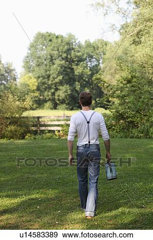 Stock Photo - Young man with watering can. Fotosearch