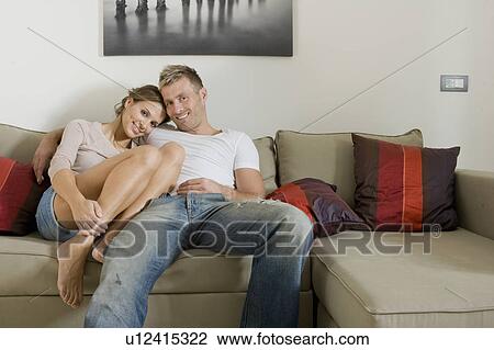 Young smiling couple relaxing on sofa View Large Photo Image Stock Image - Young smiling couple relaxing on sofa. Fotosearch
