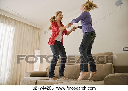 Young woman and girl jumping on sofa View Large Photo Image Stock Photography - Young woman and girl jumping on sofa. Fotosearch