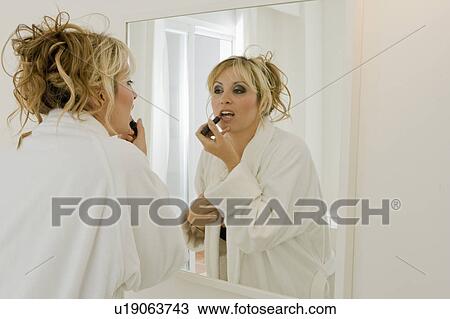 Young woman applying lipstick in mirror View Large Photo Image Stock Image - Young woman applying lipstick in mirror. Fotosearch