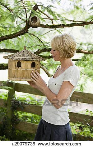 Stock Photograph - Young woman examining a birdhouse. Fotosearch