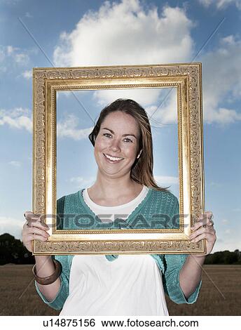Young woman, holding frame up to face View Large Photo Image Stock Photograph - Young woman, holding frame up to face. Fotosearch