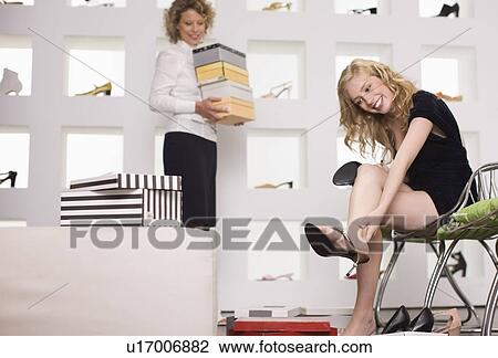 Stock Image - Young woman in a shoe shop. Fotosearch