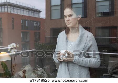 Stock Photography - Young woman looking out of window. Fotosearch