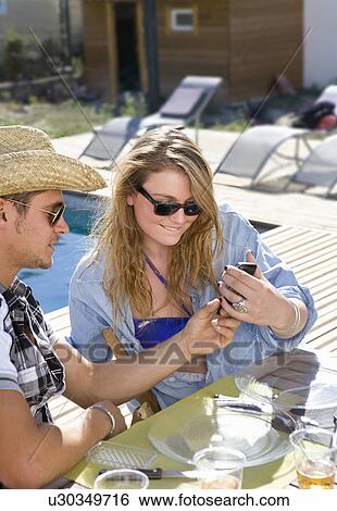 Young woman looks at phone with guy View Large Photo Image Stock Photograph - Young woman looks at phone with guy. Fotosearch