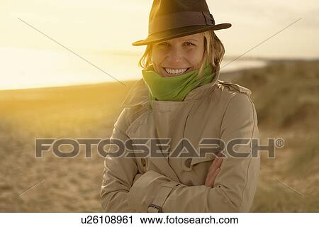 Young woman on beach in hat and raincoat View Large Photo Image Stock Image - Young woman on beach in hat and raincoat. Fotosearch